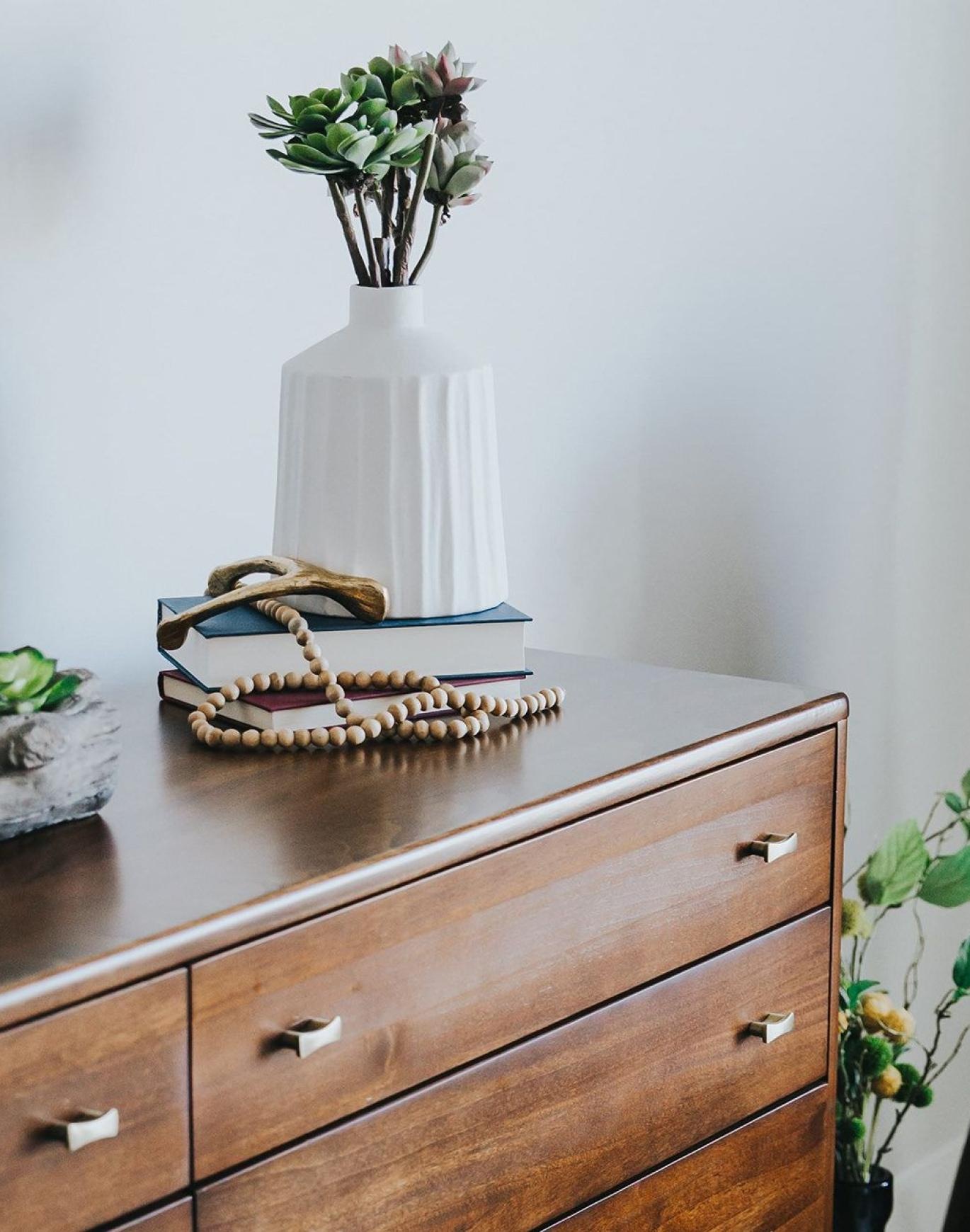 a dresser with a vase of plants on top